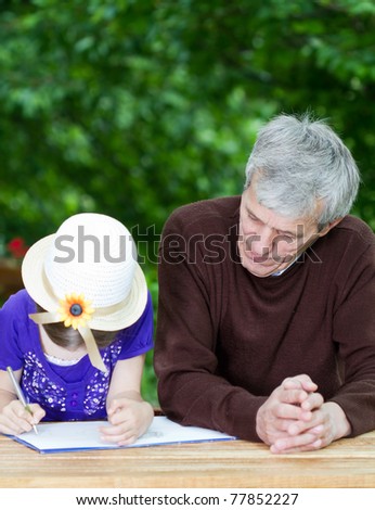 Grandfather spending time with little girl outside-little girl learning to write