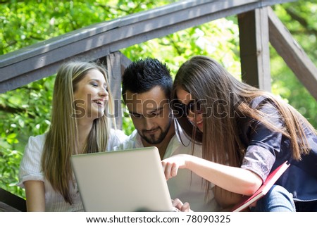 Group of three young people using laptop outdoor
