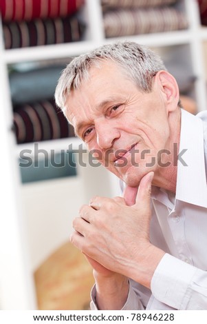 Happy elderly man portrait - sitting on sofa indoor