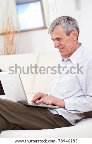 Excited senior business man working on a laptop indoor