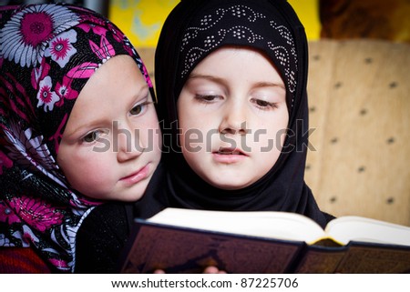 Two little muslim girls reading Holy Book Koran