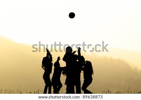 Group of children playing with ball on sunset - silhouetted