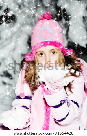 cute little girl in warm hat and gloves has a fun in snow