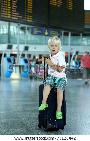 Cute boy sitting on baggage at the airport