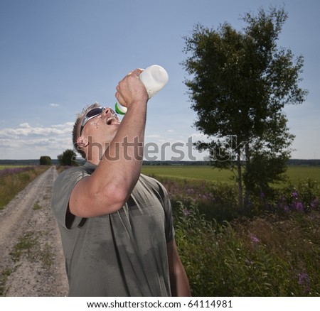Male athlete drinking water on hot summer day.