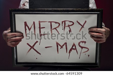Bloody fingers hold a Merry christmas sign, written with blood.