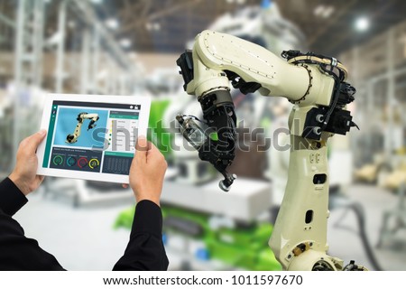 iot industry 4.0 concept,industrial engineer using software (augmented, virtual reality) in tablet to monitoring machine in real time.Smart factory use Automation robot arm in automotive manufacturing