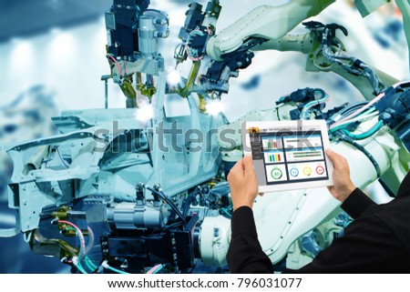 iot industry 4.0 concept,industrial engineer using software (augmented, virtual reality) in tablet to monitoring machine in real time.Smart factory use Automation robot arm in automotive manufacturing