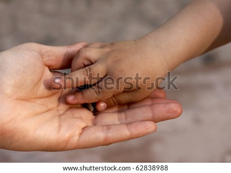 Child`s hand on mother`s hand on brawn background