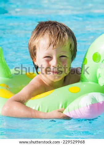 Blond boy in a swimming ring in a pool.