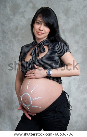 A happy pregnant girl with the sun painted on the belly