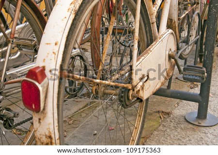 Old rusty parked bicycle in Italian town with other bicycles