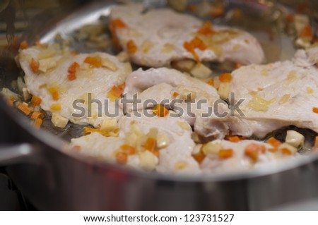 Turkey breast cooking in stainless steel pan with vegetables on gas stove  (italian recipe)