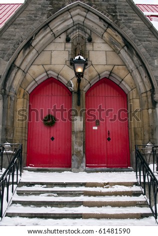 red church door with stairs in winter snow
