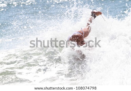 girl duck diving under wave