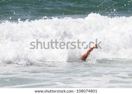 girl duck diving under wave