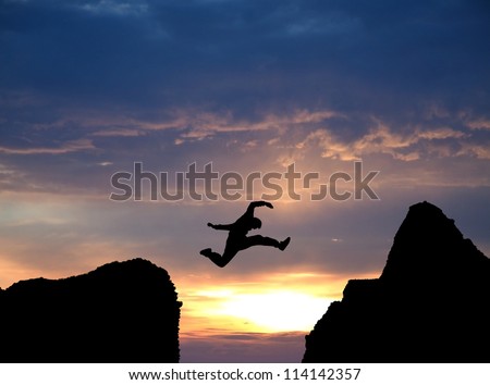 silhouette of man jumping over rocks in sunset