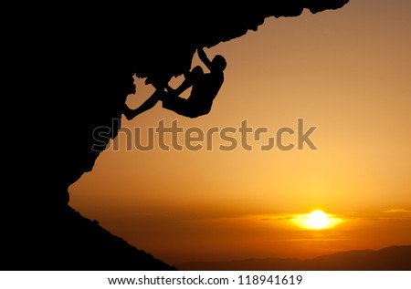 silhouette of man climbing on overhanging rock
