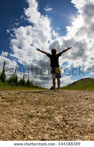 man standing on path with arms high in the sky