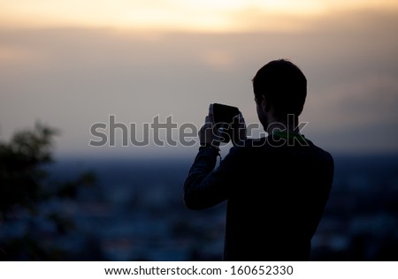 silhouette of man taking pictures with his smartphone