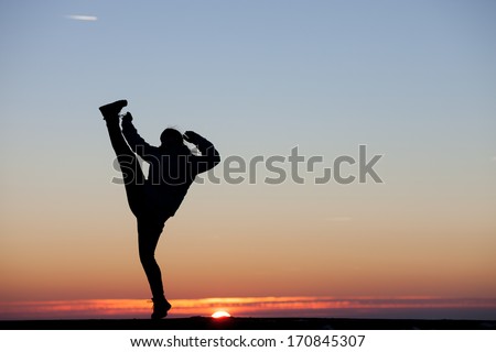 girl kicks his leg in the air in sunset sky