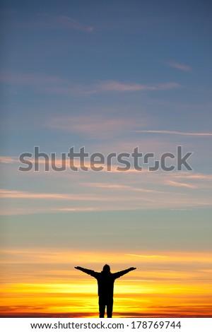 silhouette of man spreading arms in sunset sky