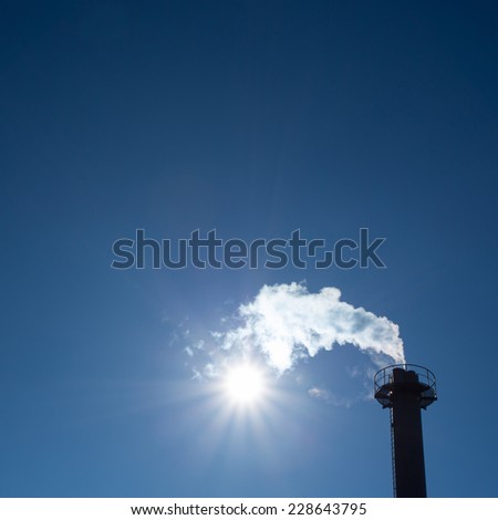 industrial chimney exhausting steam in blue sky