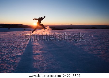 silhouetted man running through snow in winter landscape