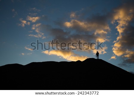 man standing on hill at sunset