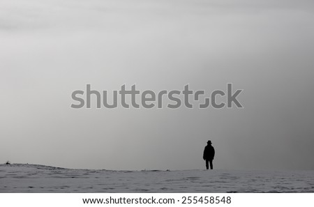elderly silhouetted man in winter landscape above fog