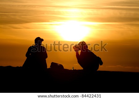 silhouette of photographer and model in sunset at beach