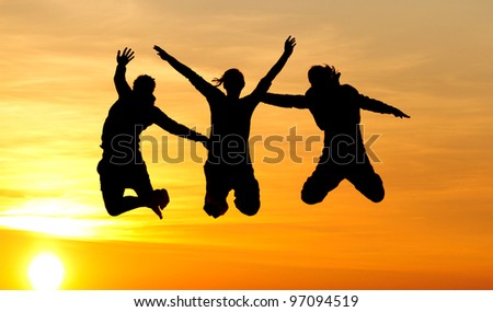 silhouette of female friends jumping in sunset