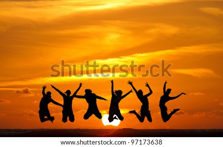 silhouette of friends jumping in sunset at beach