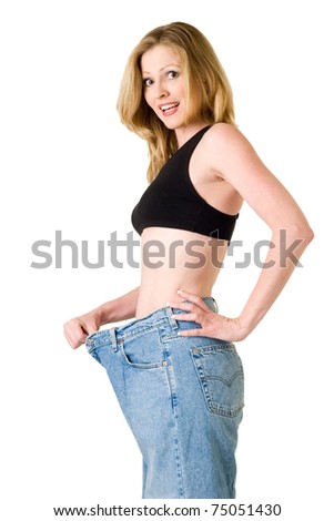 Attractive slim blond woman demonstrating weight loss by wearing an old pair of jeans and holding out to show how big the pants are