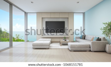 Sea view living room of luxury beach house with glass door and wooden terrace. Large white sofa against blue wall near TV in vacation home or holiday villa for big family. Hotel interior 3d rendering.