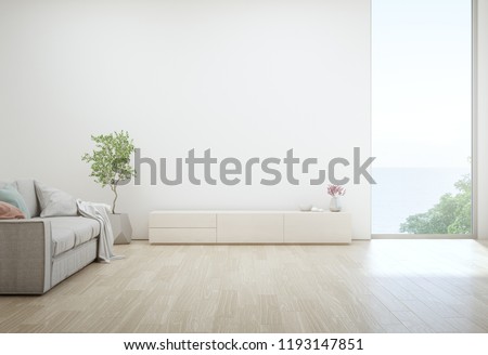 Sea view living room of luxury summer beach house with TV stand and wooden cabinet. Empty white concrete wall background in vacation home or holiday villa. Hotel interior 3d illustration.