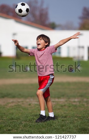 Boy preparing to kick high soccer ball in the park - Authentic action sports - copy space top - portrait format
