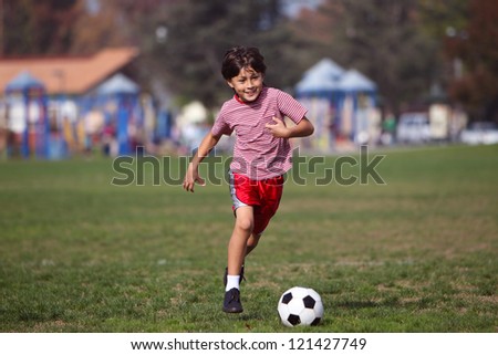 Boy playing soccer in the park - Authentic action with soccer ball - copy space right and left - landscape format