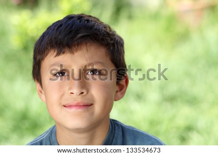 Young boy outside looking up with natural green background - copy space to right