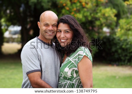A happy mixed race couple relax outside in the back yard or garden - with copy space