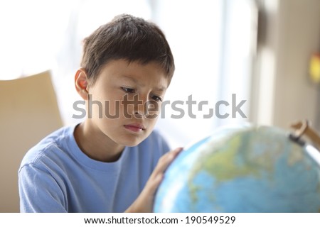 Young boy looking at a globe dreams of traveling the world - very shallow depth of field