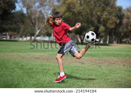 Young boy kicks a soccer ball in the park - Authentic action