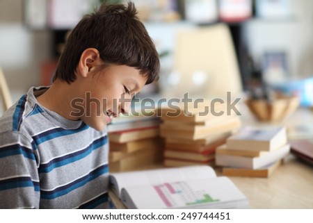 A young boy smiles as he reads a book