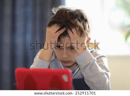 Young boy confused or frustrated boy looking at a computer tablet