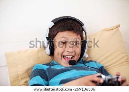 Young surprised boy playing video game with his friends with headset and microphone with copy space