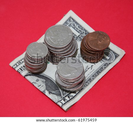 Dimes, quarters, cents and nickels piled on a dollar bill on red background