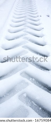 A closeup of the tire print of a truck in snow