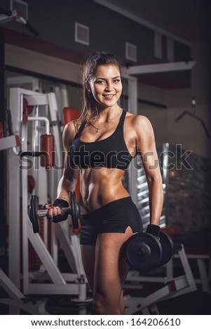 Sexy athlete with a dumbbell in the gym