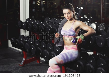 Fitness girl with towel and shaker relaxing in the gym
