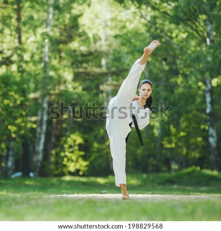 karate girl makes high kick on forest location